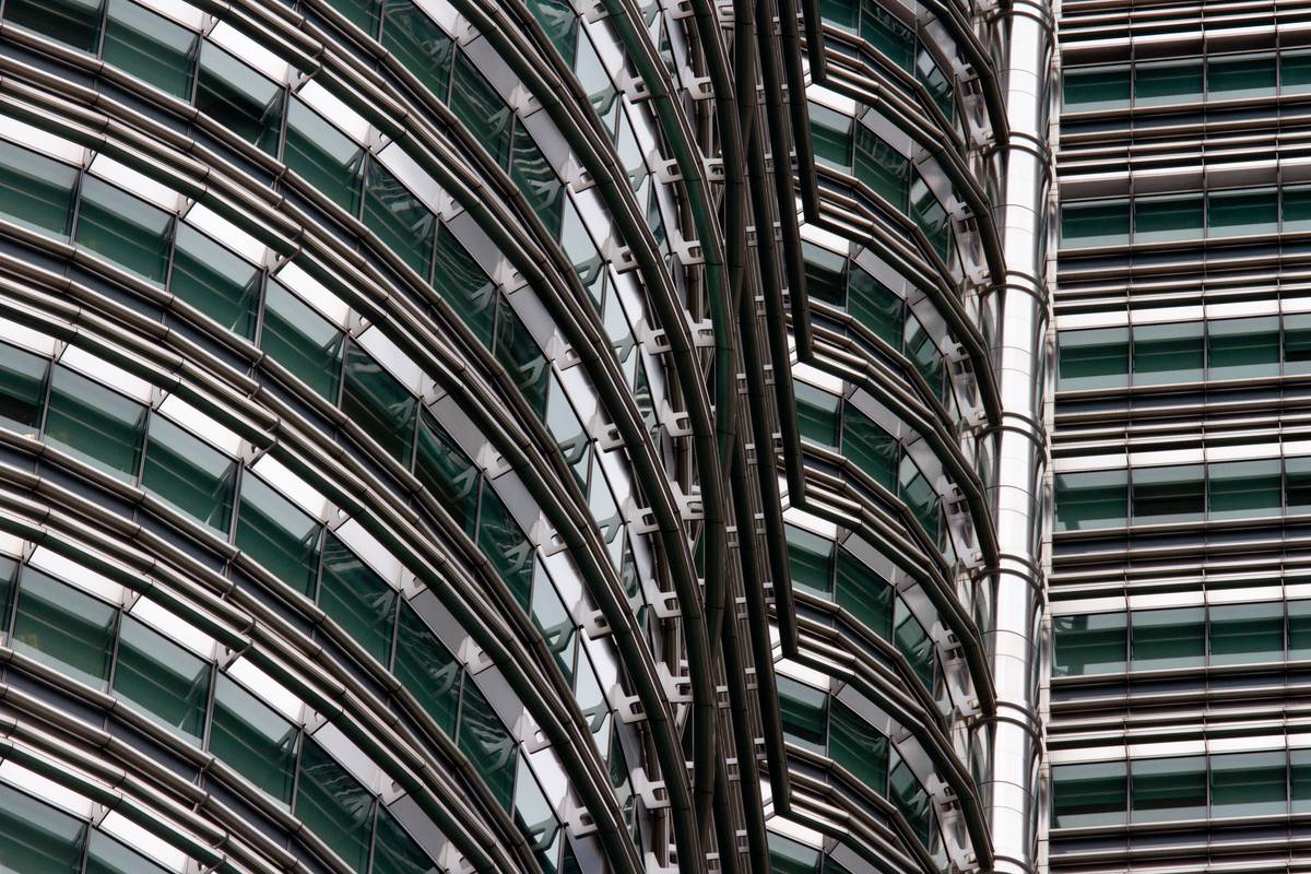 Steel and glass facade of the Petronas Twin Towers reflects ambient light on an overcast day.