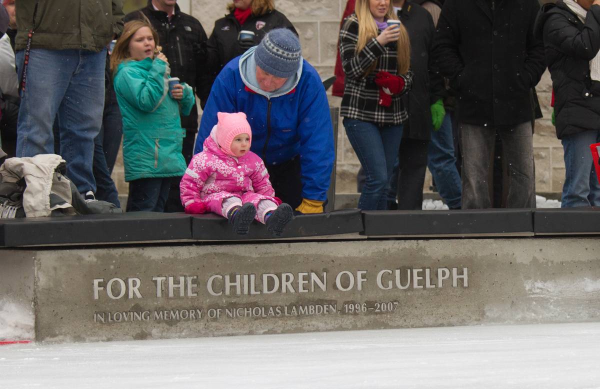 A toddler sits atop the concrete benches on the edge of the skating rink, itself adorned with whom the rink was dedicated to. Part of the funding for this rink came from the [Nicholas Lambden Memorial Children's Foundation](http://www.nicklambden.com/).