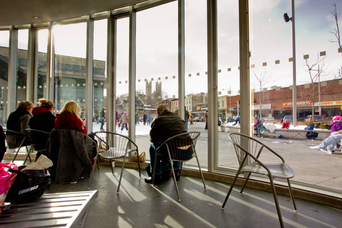 Non-skaters huddle together in the comfort of heated air and afternoon sunshine as they enjoyed the view out into the skating rink.