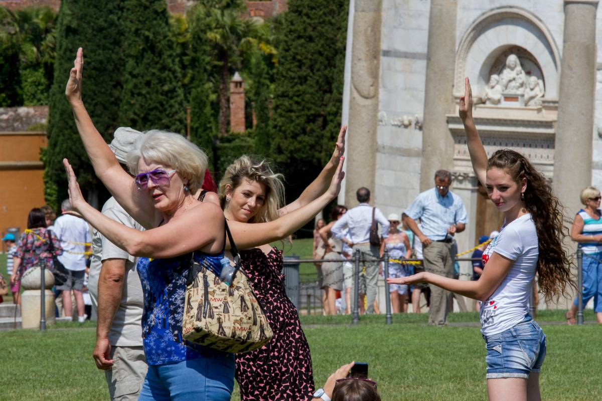 Tourists posed in front of the tower pretending to hold up the leaning structure