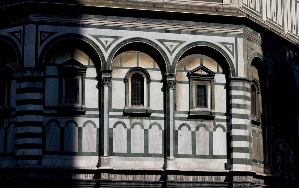 Noon sunshine falls on *Battistero di San Giovanni* (Baptistry of St. John), which stands across the cathedral