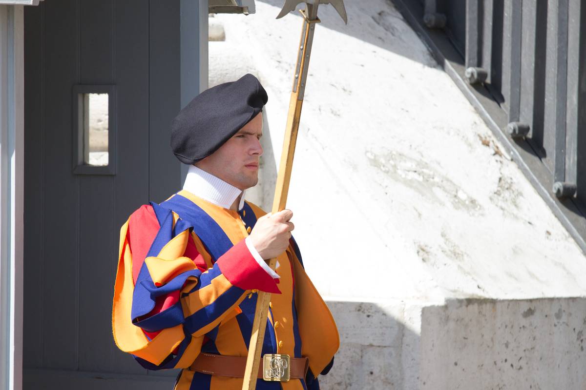 A Swiss Guard standing guard at the gate next to St. Peter's Basilica