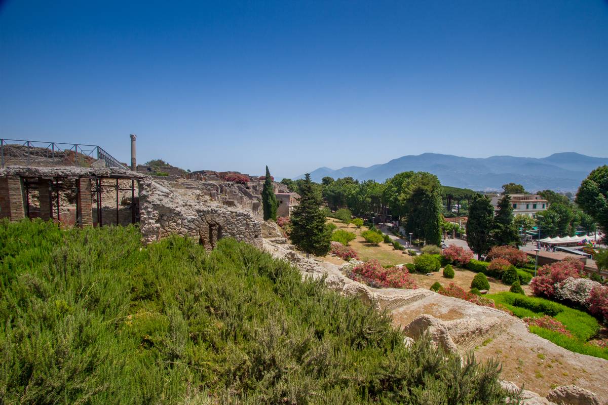 Southern walls of ancient Pompeii in view, with the mountains of the Sorrento Peninsula visible in the far background
