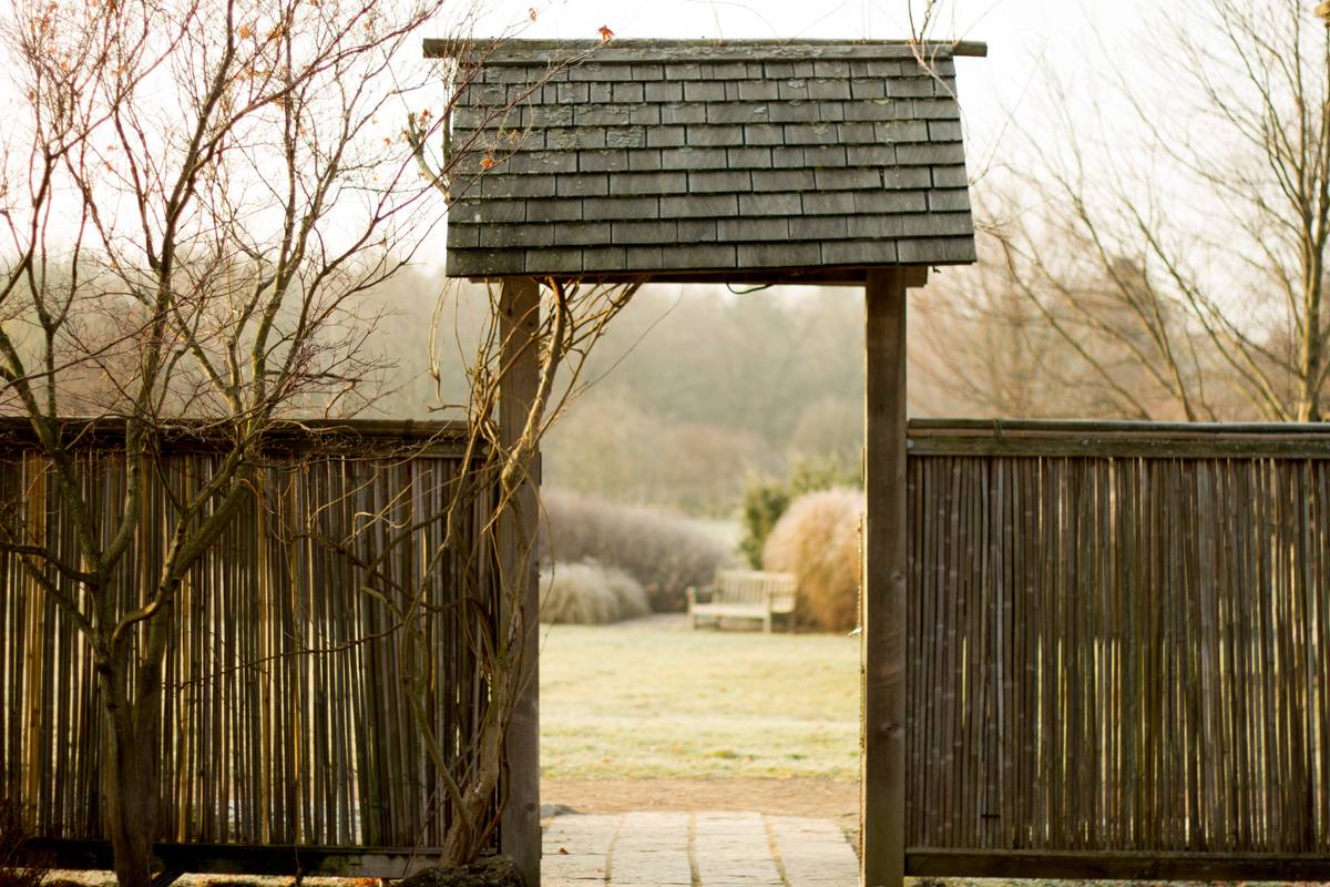Bamboo lined fences open to a roof-topped entrance