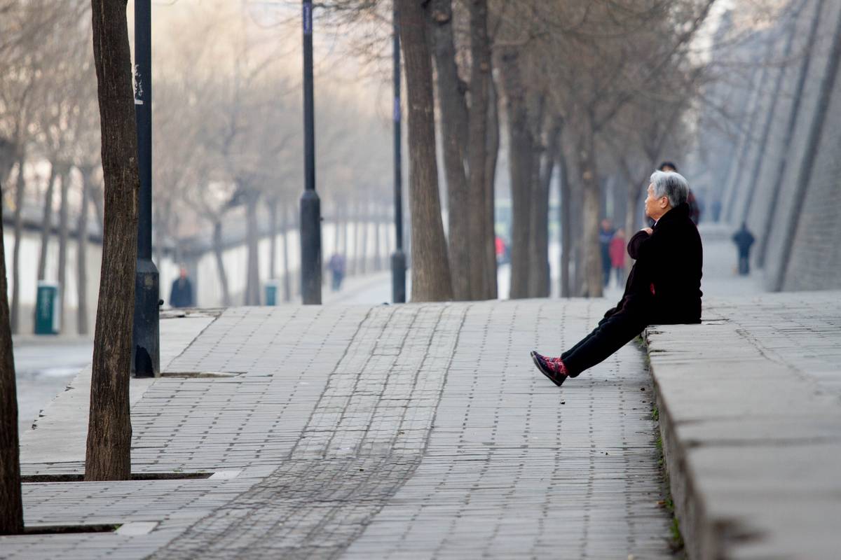 A woman sits near the walls of Xi'an.