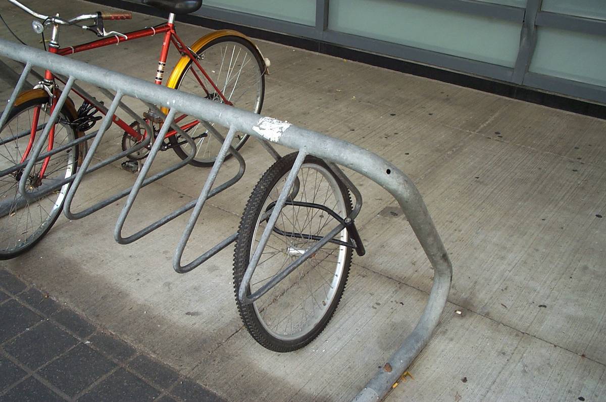 Picture of a bicycle wheel locked to a bike rack, the rest of the bike missing. Shot in Toronto