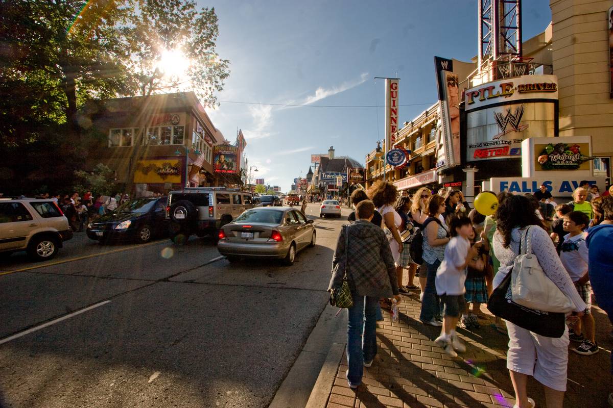 Clifton Hill, Niagara Falls, teamed with vacationers of the long weekend in the United States, as the Sun begins to set behind buildings