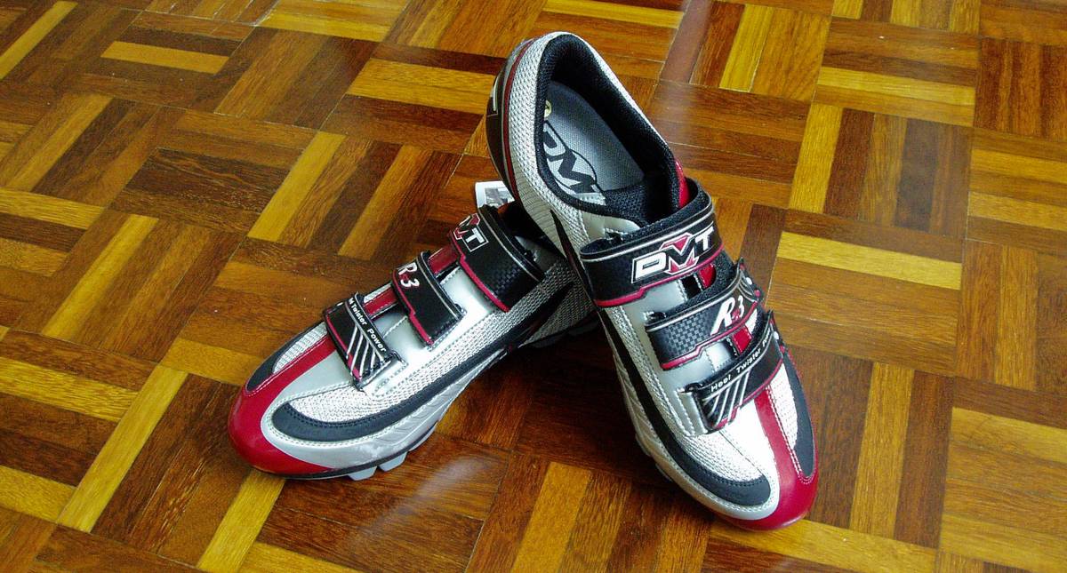 A pair of brand new DMT RS3 cycling shoes carefully placed on a wooden tile floor