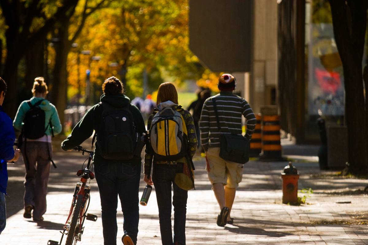 Looking at a crowd of university students walking away on a corridor as the autumn leaves blurs in the background
