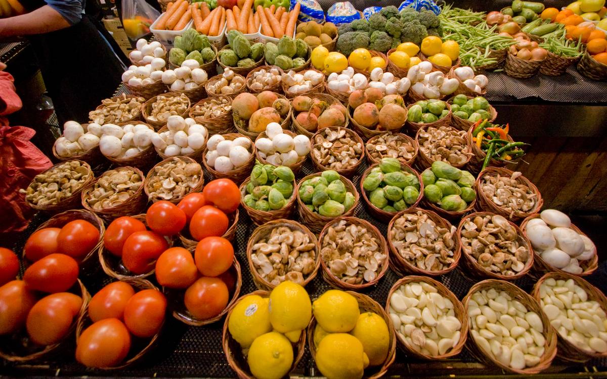 Fresh tomatoes, mushrooms, and other farm products sold by the wicker basket.