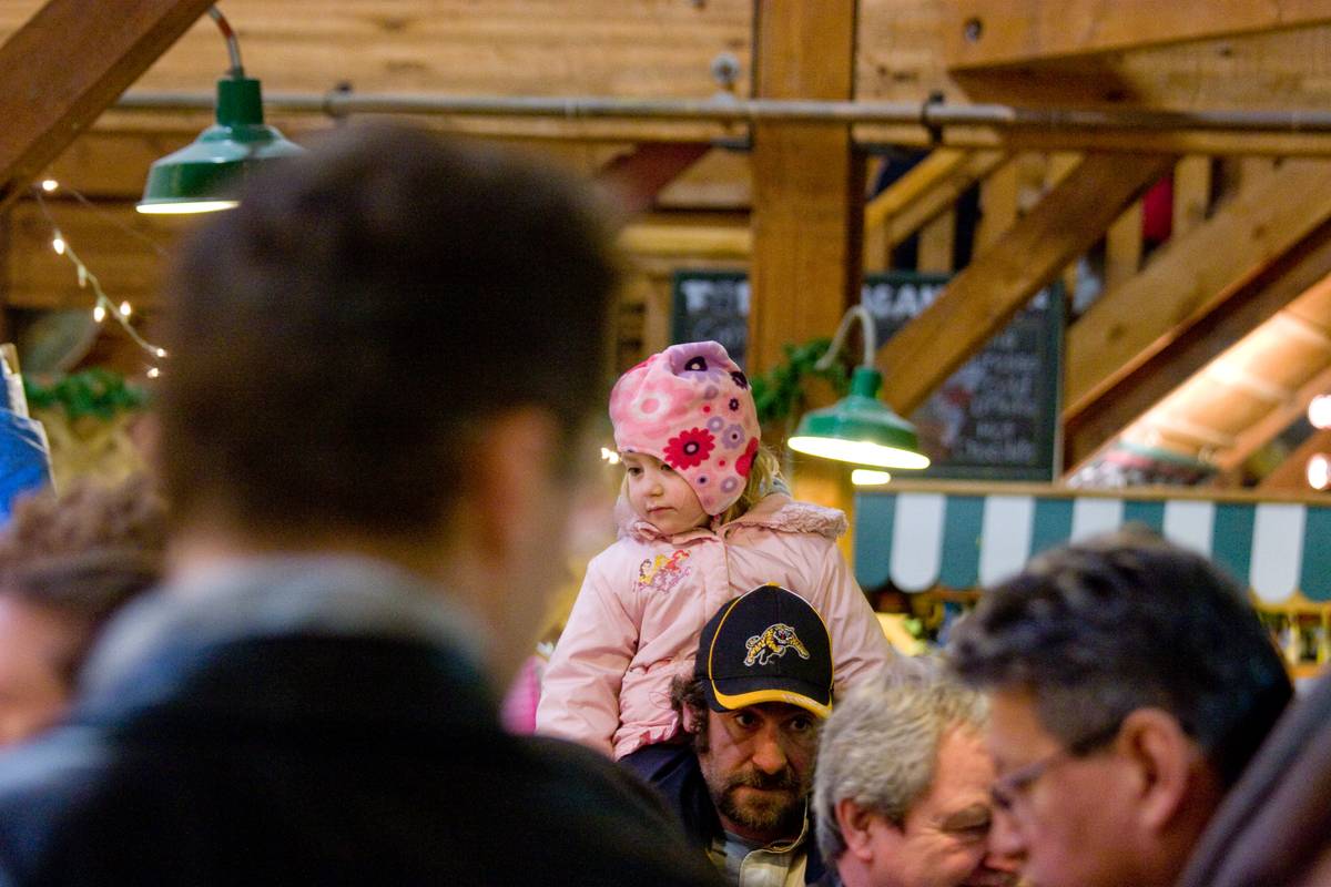 A young girl carried on the shoulder as she meanders through the crowd. Using a stroller in the crammed market is a bad idea.