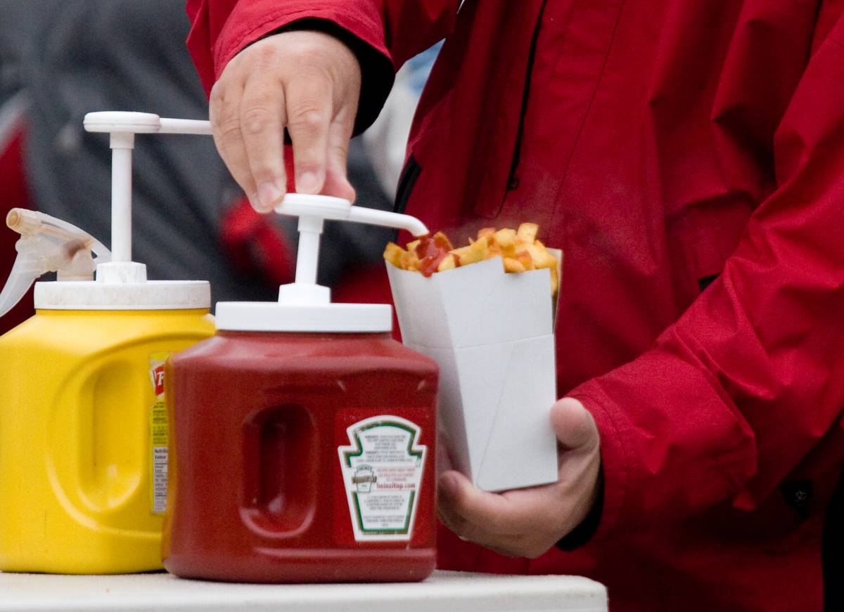 A man applies ketchup onto his serving of fresh-cut fries.