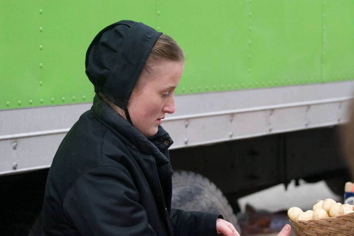An Amish woman tends to her vegetable stall.