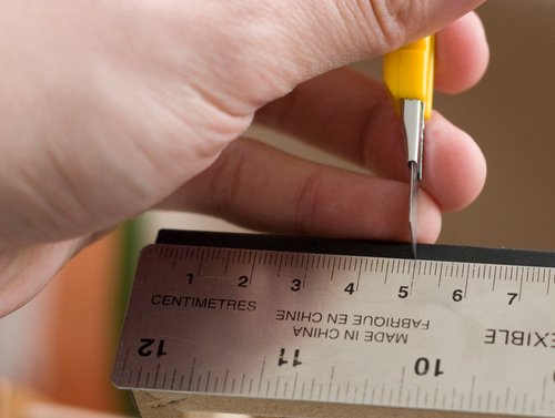 Marking the 5cm line using a metal ruler and a knife